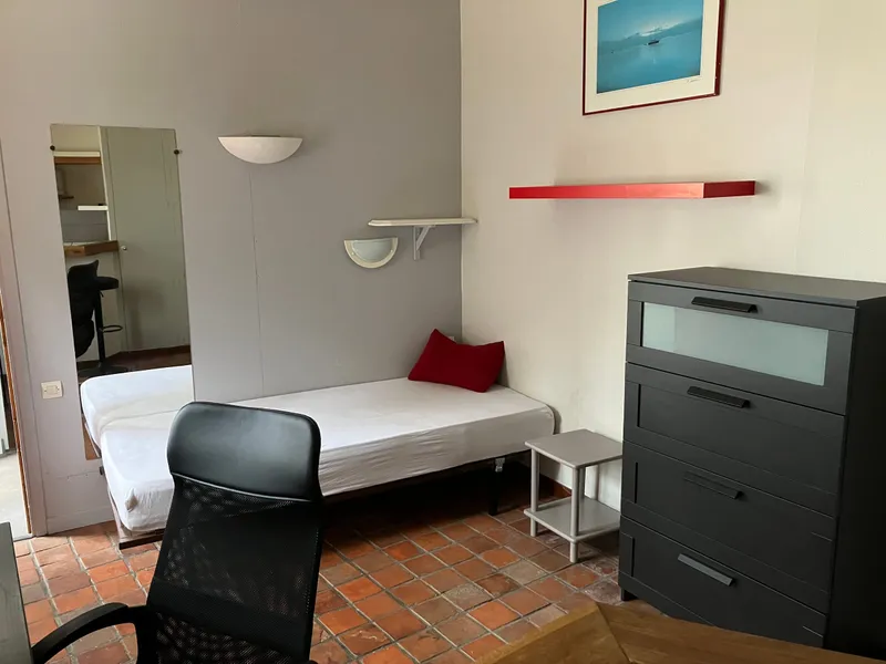 Sleeping area of the studio with bed, chest of drawers and mirror